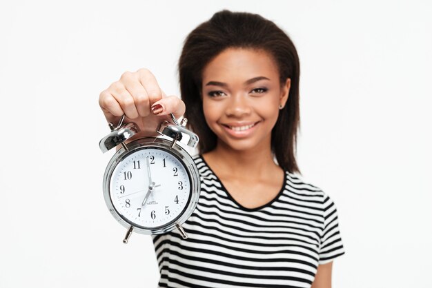 Portrait of a happy african teen woman showing alarm clock