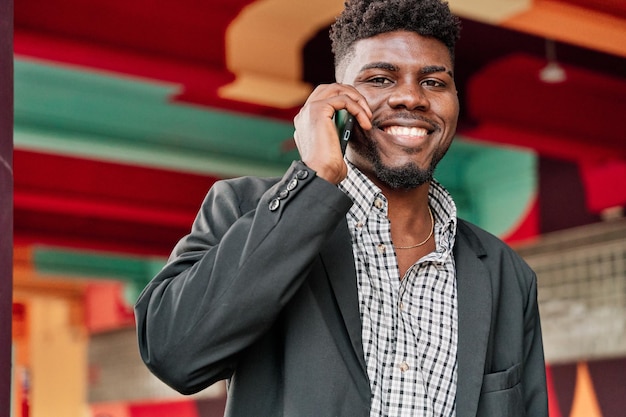 화려한 도시 배경을 가진 스마트폰으로 말하는 행복한 아프리카계 미국인 남자의 초상화