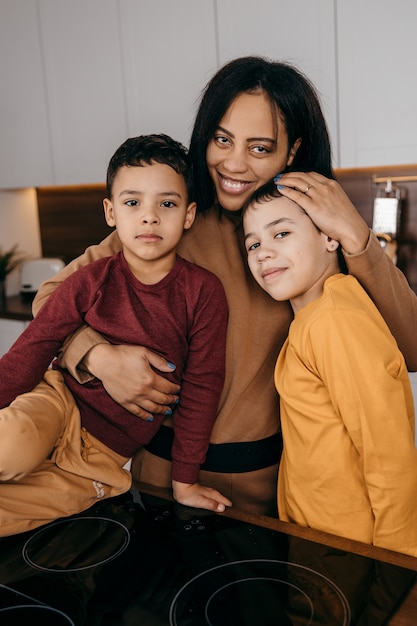 Portrait of happy afro american family in the kitchen, mom and two sons looking at the camera