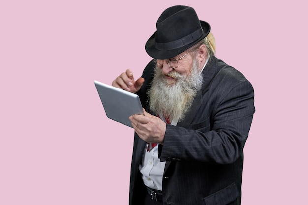 Photo portrait of happy aged man with tablet pc isolated on pink