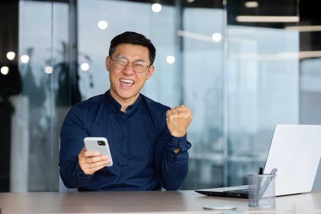 Portrait of happy asian businessman man celebrating achievement\
good results and victory boss