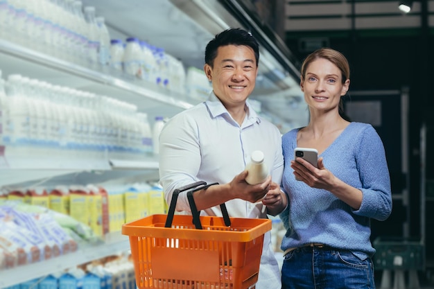 Portrait of a happy asian couple of consumers supermarket shoppers or grocery store looking at