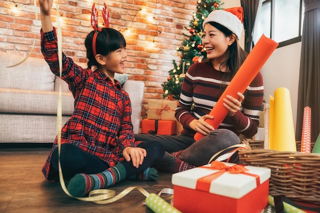 Portrait of happy Asian family little girl help her mother wrapping gift box, celebration holiday christmas. young mom and girl are doing handcraft activity enjoying wrap gifts.