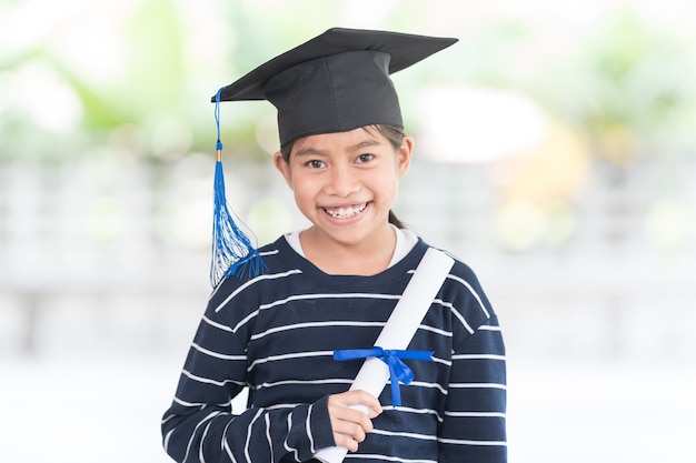 Portrait happy asian female school kid graduate in a graduation
cap holds a rolled certificate. graduation celebration concept
stock photo