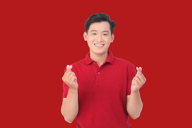 Портрет счастливого азиатского человека, делающего сердце пальцами, изолированными на белом фоне