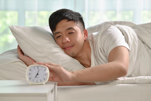 Portrait of happy Asian man waking up in bed in the morning