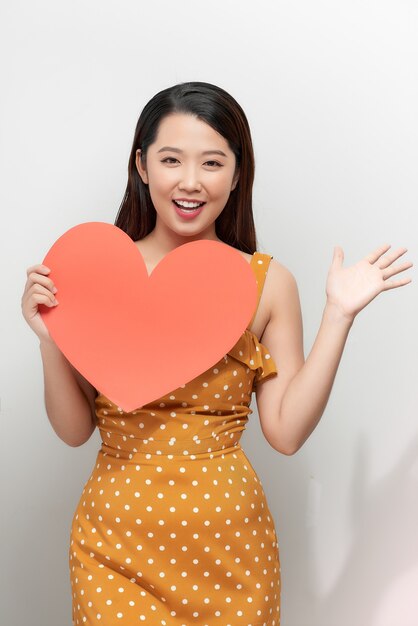 Portrait of happy asian woman holding red heart symbol