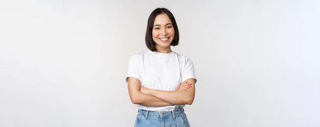 Portrait of happy asian woman smiling posing confident cross arms on chest standing against studio background