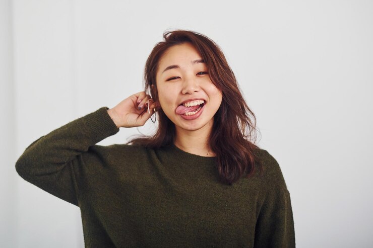 Photo 白い背景のスタジオで屋内に立っている幸せなアジアの若い女の子の肖像画。
