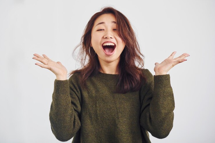 Photo 白い背景のスタジオで屋内に立っている幸せなアジアの若い女の子の肖像画。