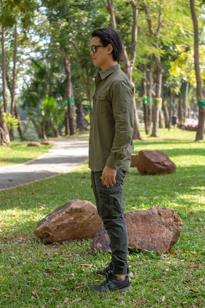 Portrait of happy asian young man in long sleeve shirt and green pant standing  in the park