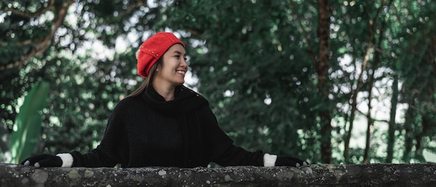 Portrait of Happy Asian young woman in winter costume at the forest with copy space Vacation and travel concept