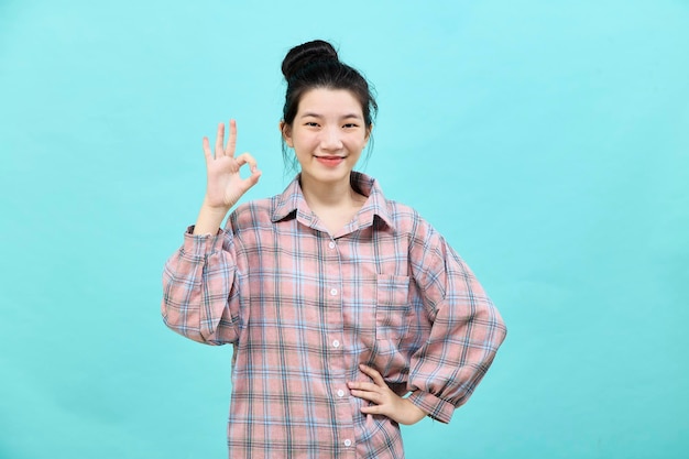 Portrait of a happy attractive young woman Asian posing in studio showing ok gesture