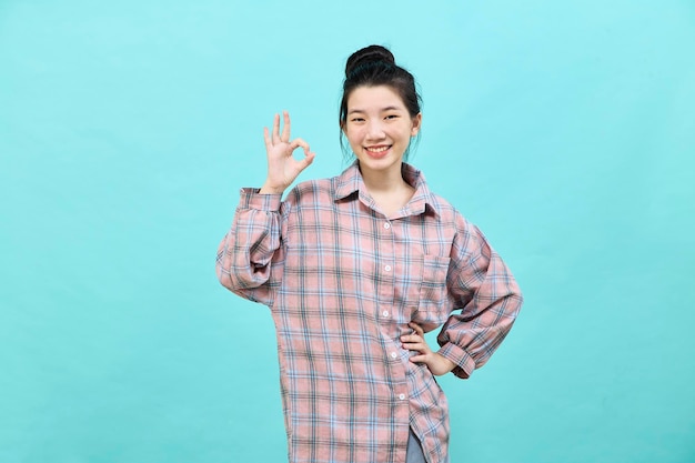 Portrait of a happy attractive young woman Asian posing in studio showing ok gesture