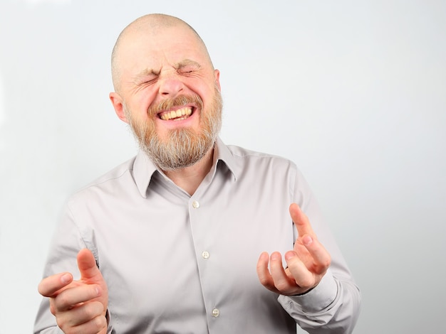 Portrait of a happy bearded man in a shirt with arms raised