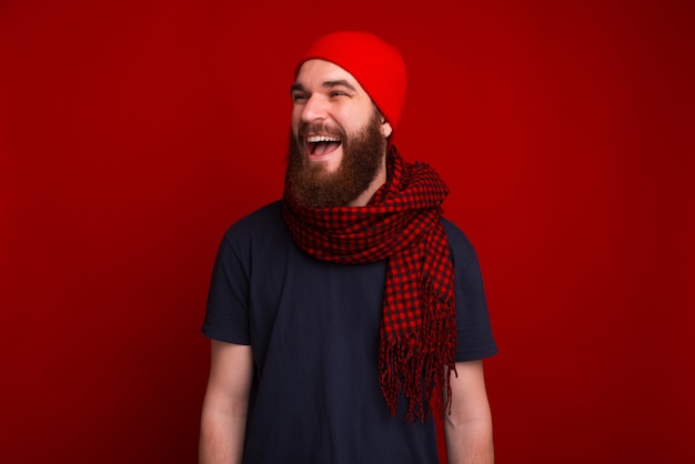 Portrait of happy bearded man wearing scarf, and hat, looking away with big smile