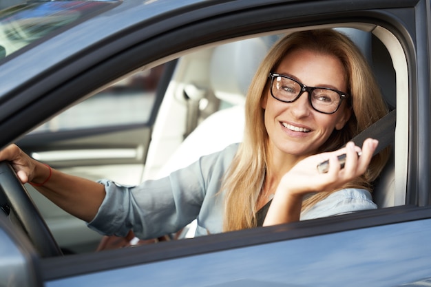 車のキーを保持し、後ろに座って笑って幸せな美しいビジネス女性の肖像画