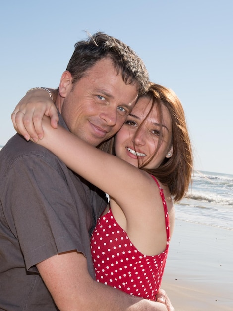 Portrait of happy beautiful couple on beach embracing