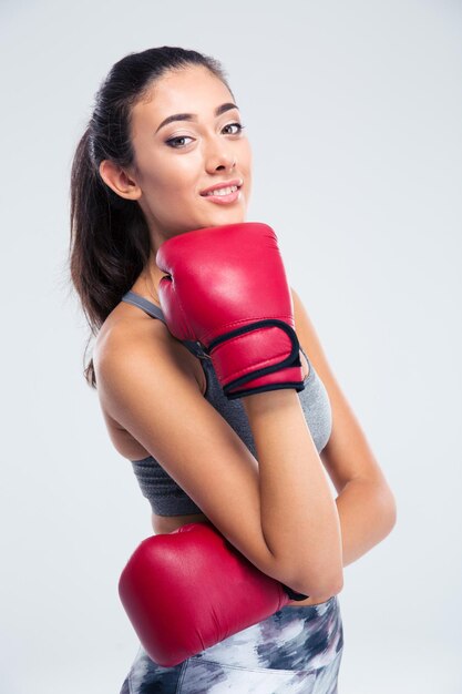 Portrait of a happy beautiful girl with boxing gloves standing isolated on a white wall