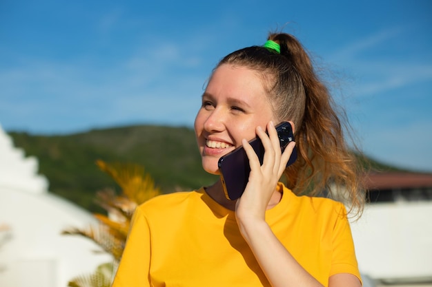 Portrait of happy beautiful girl young positive woman is talking on her cell mobile phone calling on