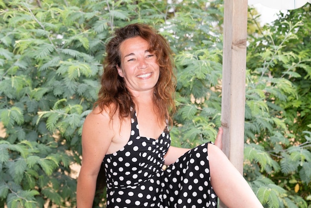 Portrait of happy beautiful middle aged brunette woman in white black dress relaxing outdoor