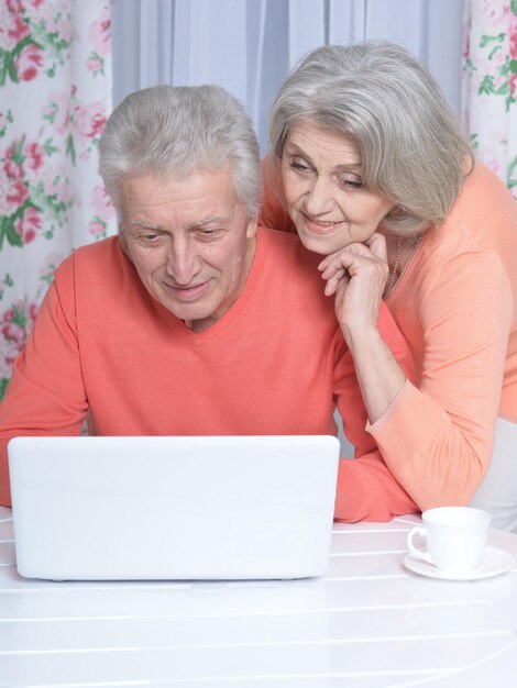 自宅でラップトップを使用して幸せな美しい年配のカップルの肖像画