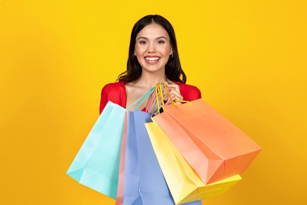 Portrait of happy beautiful woman holding bright shopping bags in hands