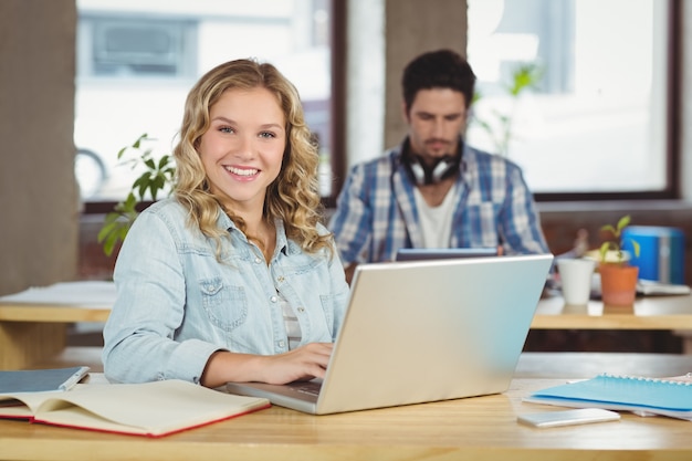 Ritratto di bella donna felice che utilizza computer portatile nell'ufficio luminoso creativo