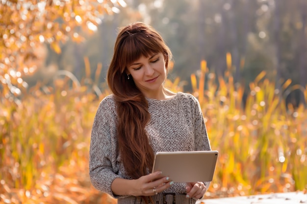 Portrait of a happy, beautiful woman with long brown hair, sitting in an autumn park