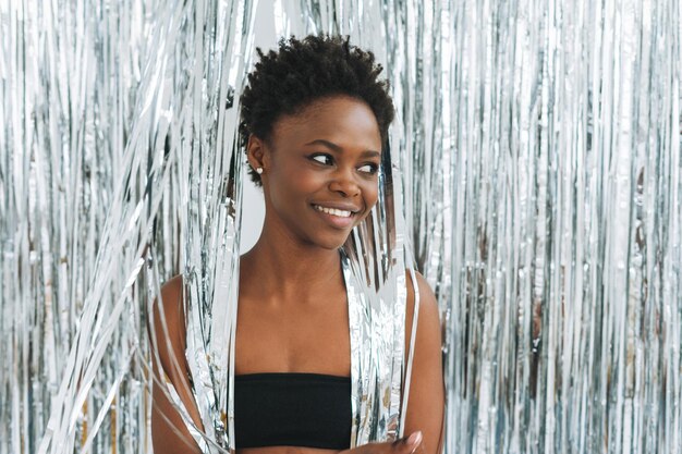 Photo portrait of happy beautiful young african american woman in black top on sparkly silver background