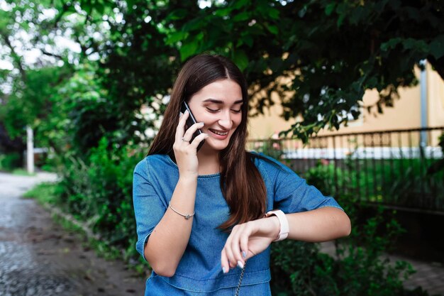 Portrait of happy beautiful young girl smiling looking and pointing finger at her smart watch Beautiful woman looking at her watch