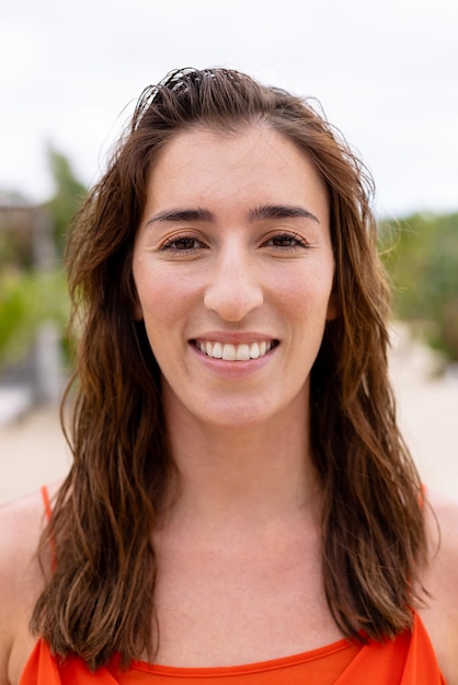 Portrait of happy biracial woman looking at camera and smiling at beach. Spending quality time, lifestyle, summertime and vacation concept.