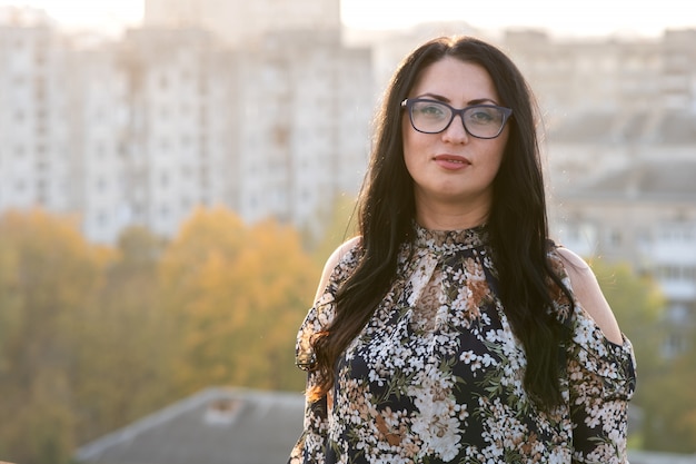 Portrait of a happy black haired woman in fashionable glasses on warm summer day outdoors.