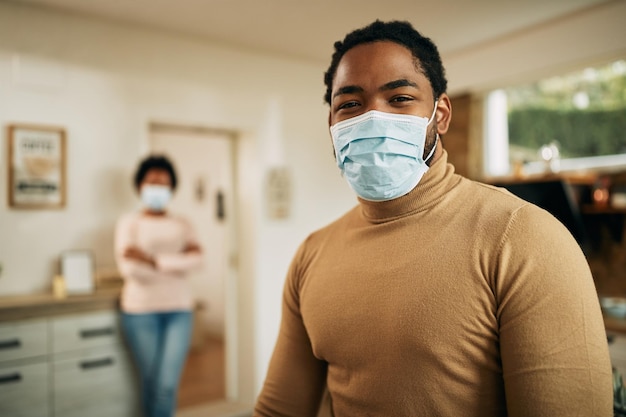 Portrait of happy black man wearing protective face mask at home