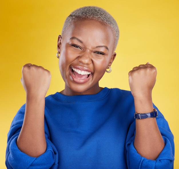 Portrait happy black woman and fist of winner in studio for celebration achievement deal and success excited female model celebrate winning prize on background for lottery bonus victory and smile