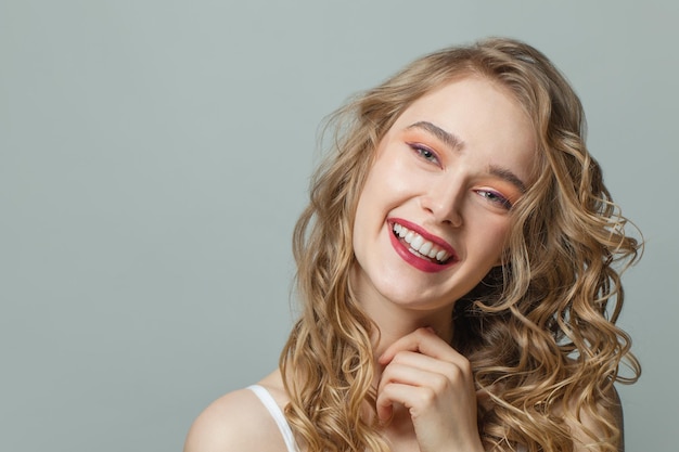 Portrait of happy blonde woman smiling on white