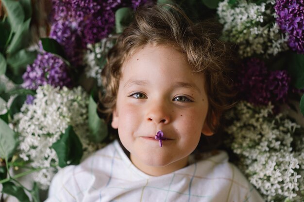 Portrait of a happy boy in lilac flowers happy childhood