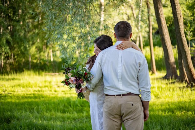 Portrait of a happy bride and groom in boho style wedding dresses against the backdrop of beautiful nature