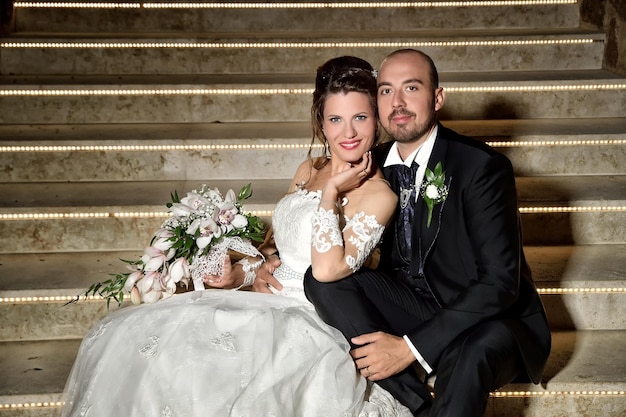 Photo portrait of happy bride and groom sitting on steps