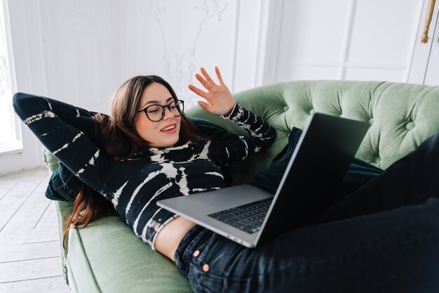 Portrait of happy brunette young woman lying on sofa at home