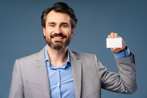 Photo portrait of happy businessman in suit showing business card posing in studio business concept