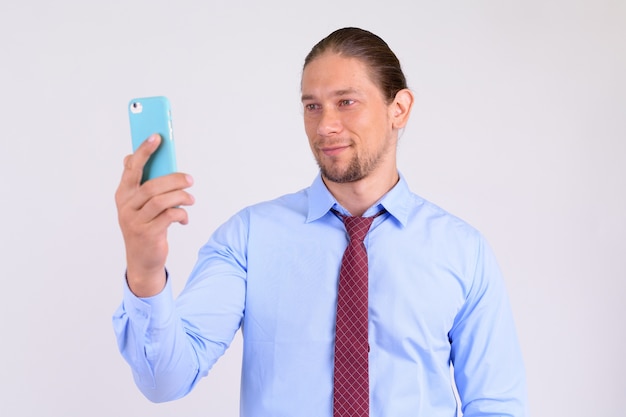 Portrait of happy businessman using phone against white backgrou