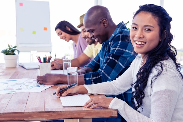 Portrait of happy businesswoman sitting with colleagues in conference room