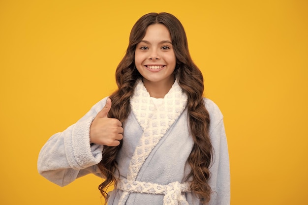 Portrait of a happy casual teenager child girl showing thumbs up and smiling