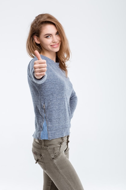 Portrait of a happy casual woman showing thumb up isolated on a white background