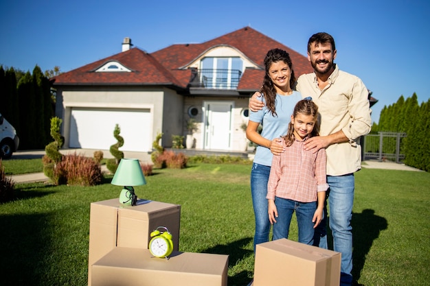 Portrait of happy caucasian family standing in front of their new house ready to move in.