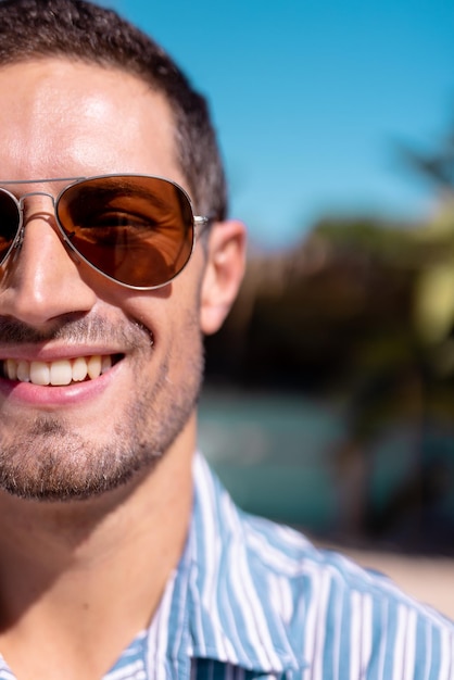 Portrait of happy caucasian man looking at camera and smiling at beach, with copy space. Spending quality time, lifestyle, summertime and vacation concept.