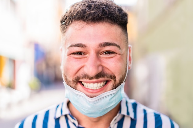 Ritratto dell'uomo caucasico felice che sorride davanti alla macchina fotografica mentre indossando maschera protettiva medica