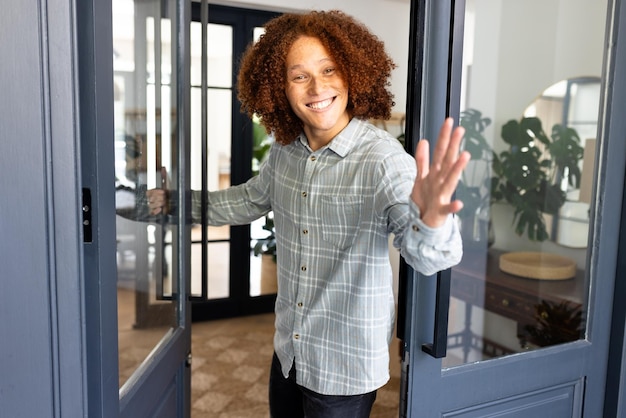 Portrait of happy caucasian man with curly hair welcoming at home