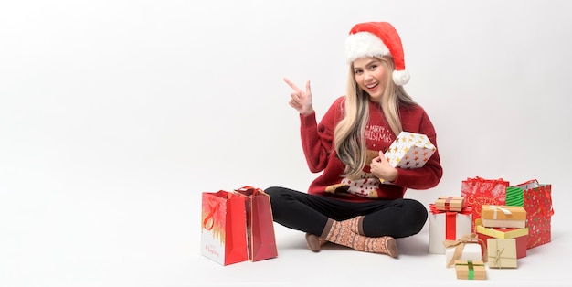 Portrait of happy Caucasian young woman in santa claus hat with gift box and shopping